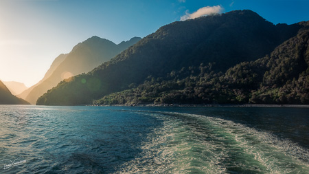 A cruise boat trail in the fjord at Milford Sound, New Zealand.