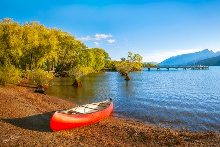 A red canoe at Glenorchy Wharf at golden hour in New Zealand